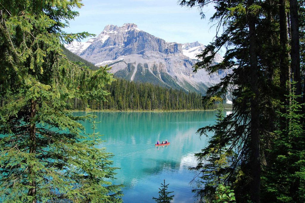 people canoeing on emerald lake