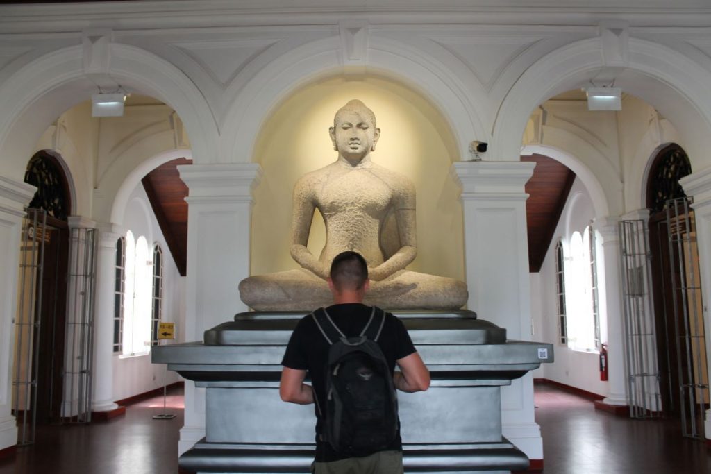 man posing at statue of buddha national museum colombo